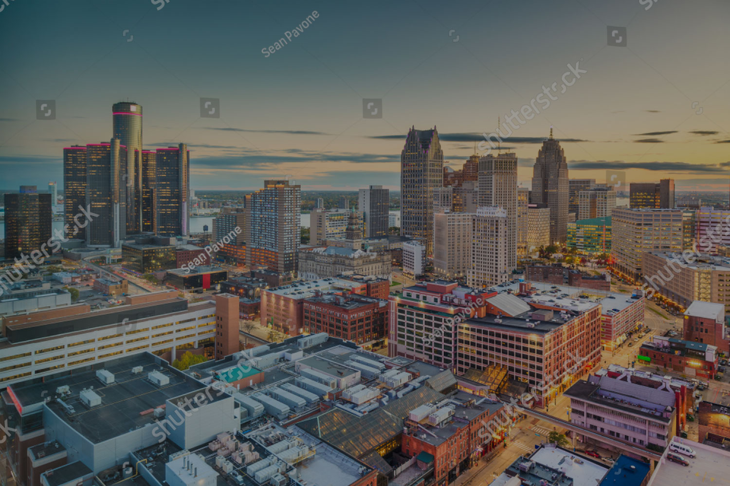 City skyline at sunset with tall buildings and cranes.