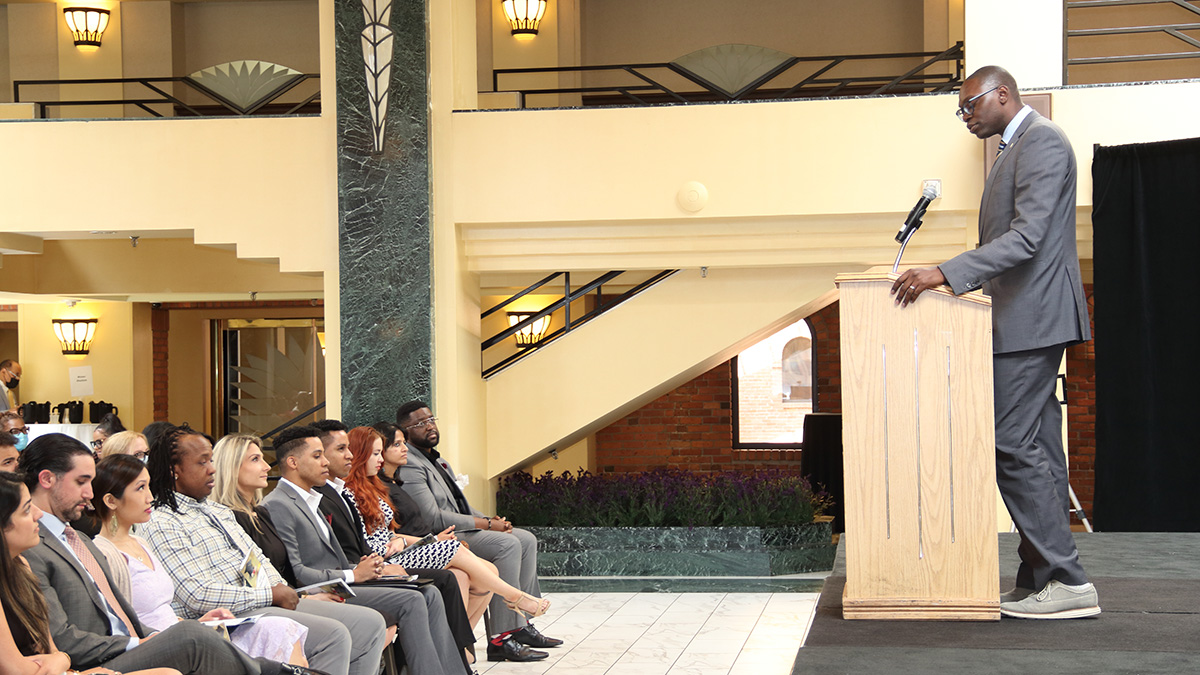 A speaker addressing an attentive audience in a formal indoor setting.