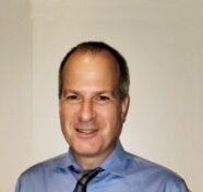 Portrait of a smiling man in a blue shirt and tie.