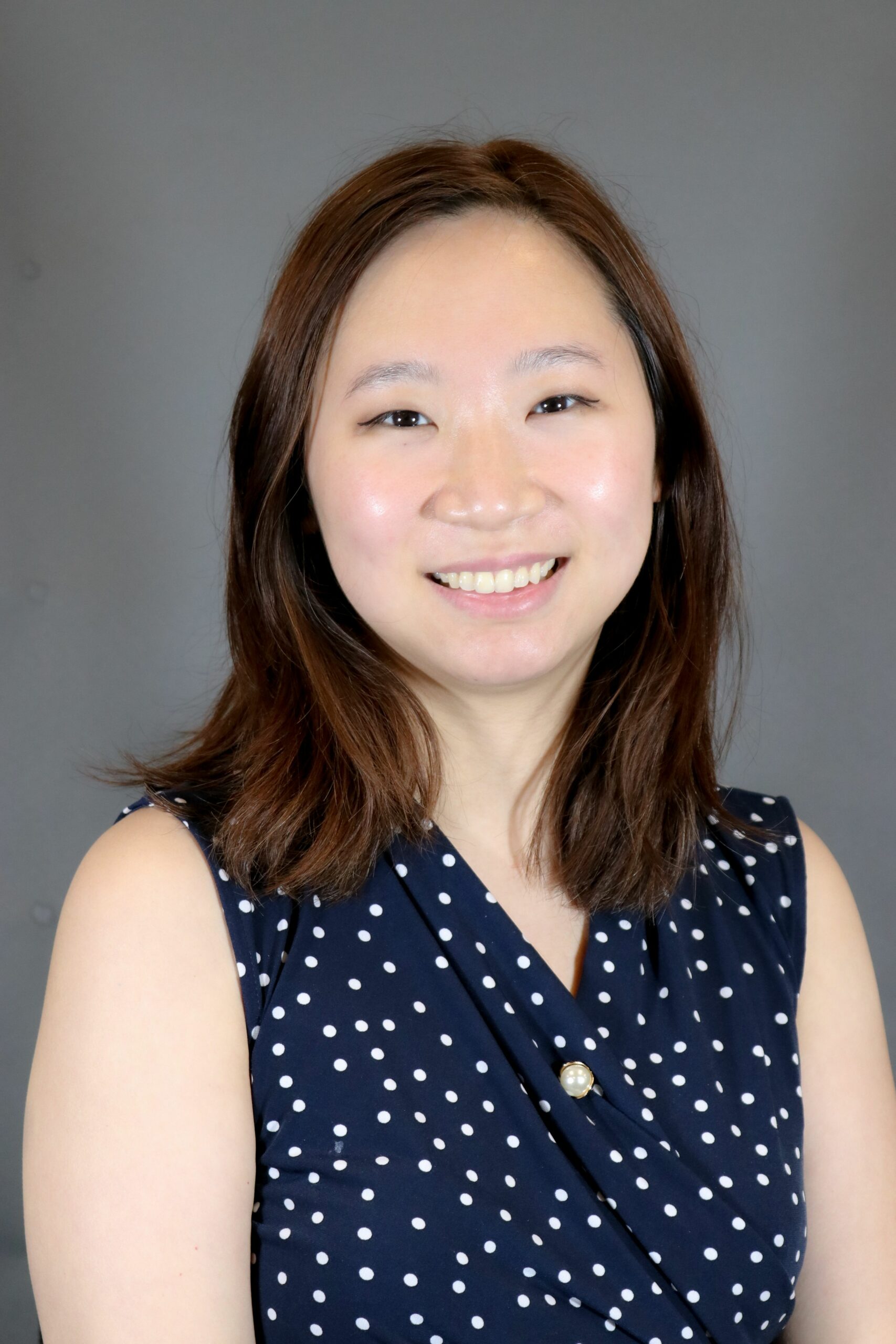Portrait of a smiling woman in a navy blue polka dot dress.