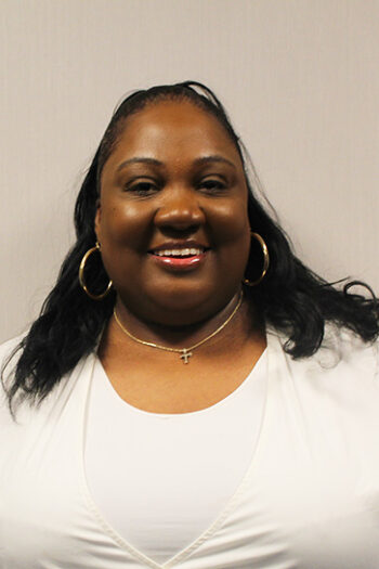 Smiling woman with hoop earrings and necklace.