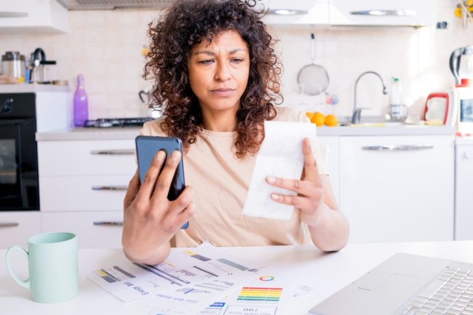 Woman comparing medication with information on her phone at home.