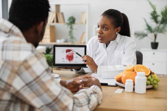 Doctor explaining heart health to a patient with a heart model and diagram.