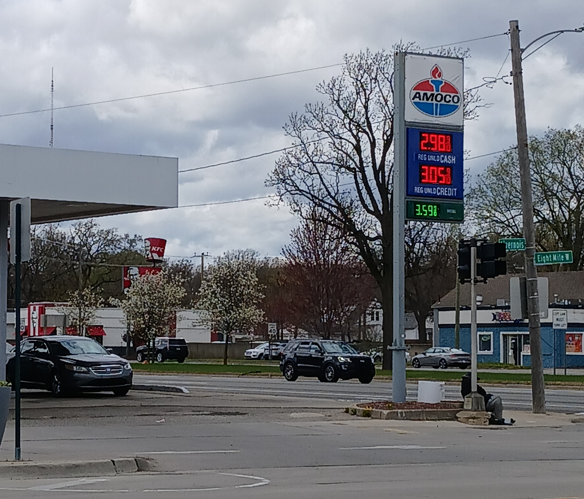 A gas station with visible fuel prices under a cloudy sky.