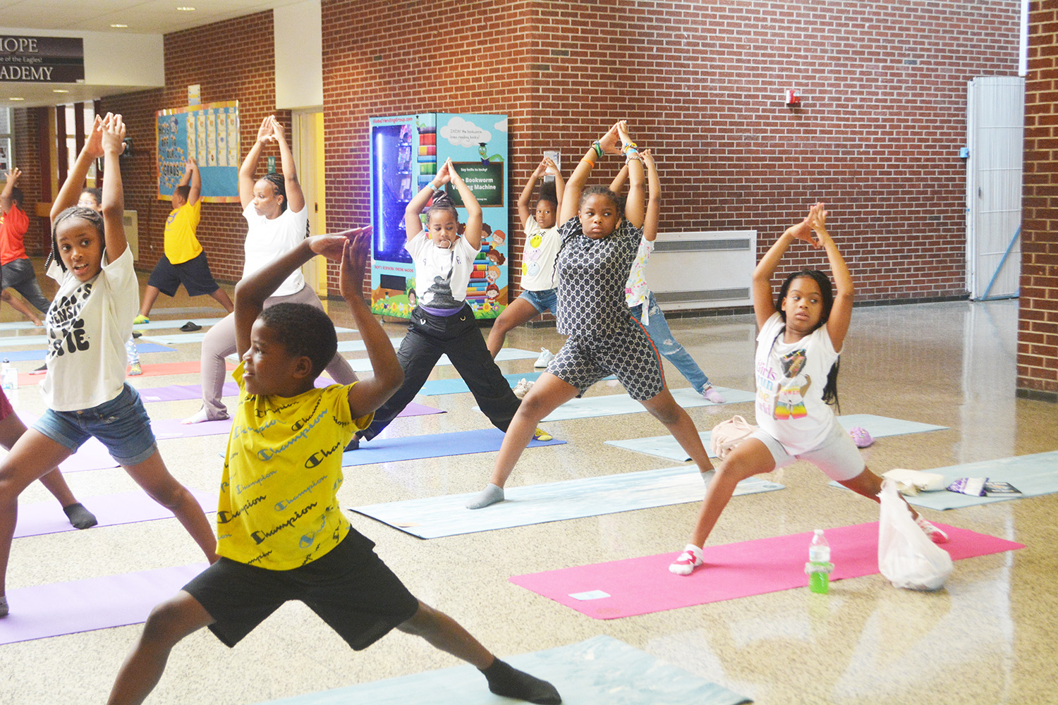Children practicing yoga in a bright room with a brick wall.