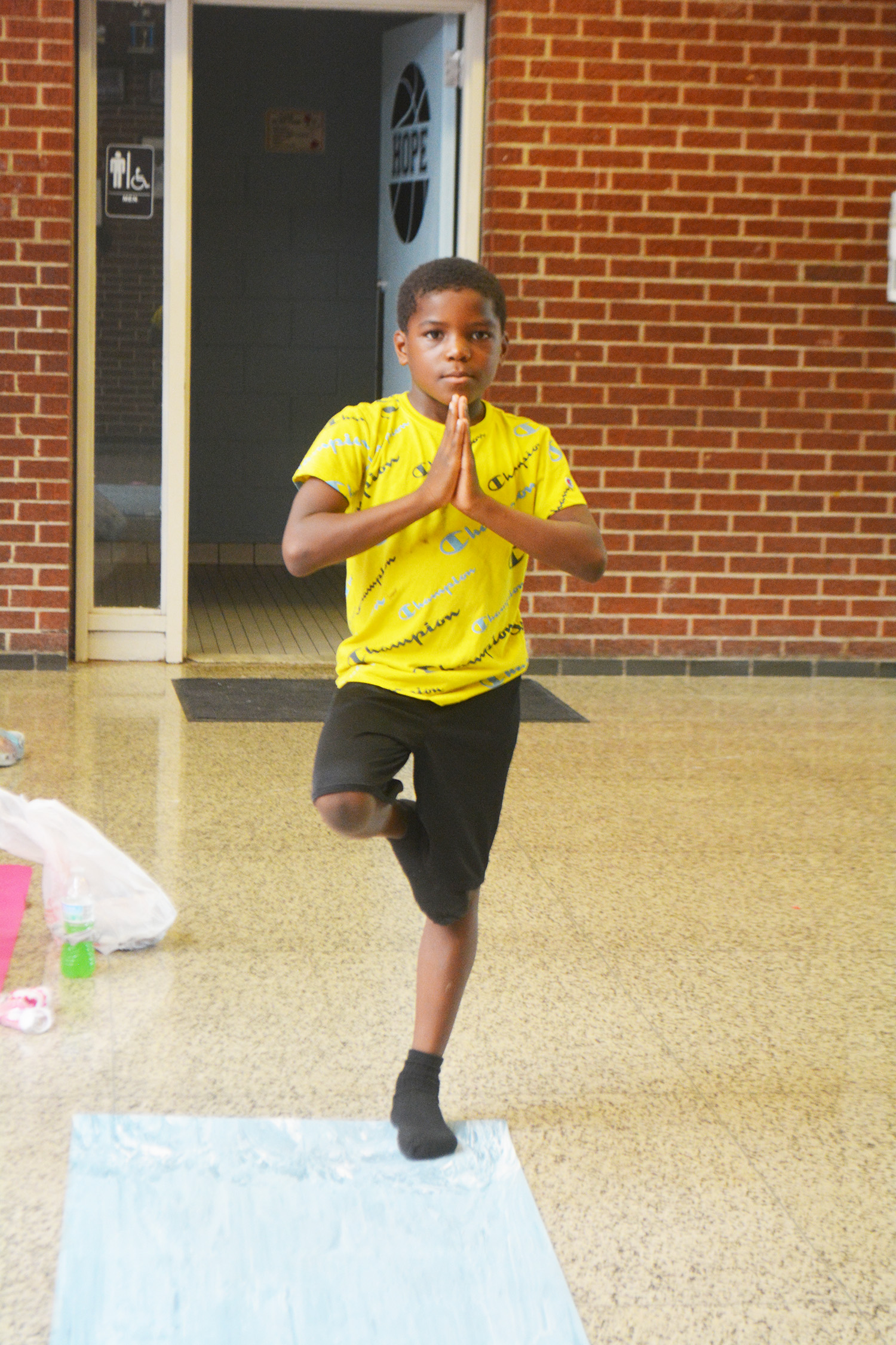 Young boy practicing yoga indoors in a balanced pose.